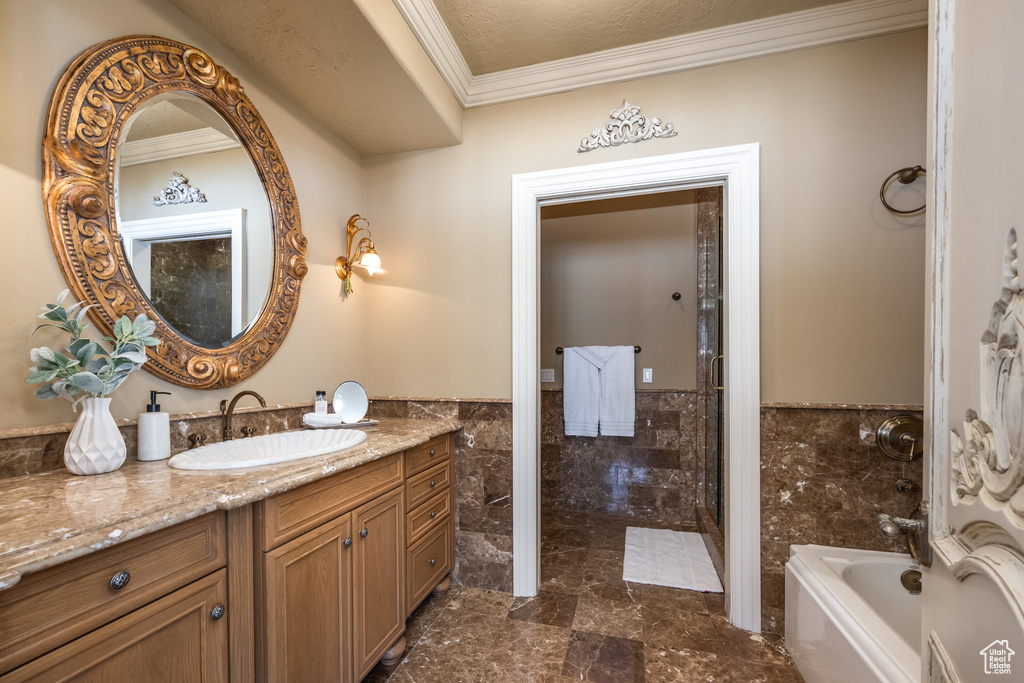 Bathroom featuring vanity, tile walls, ornamental molding, a tub to relax in, and wainscoting