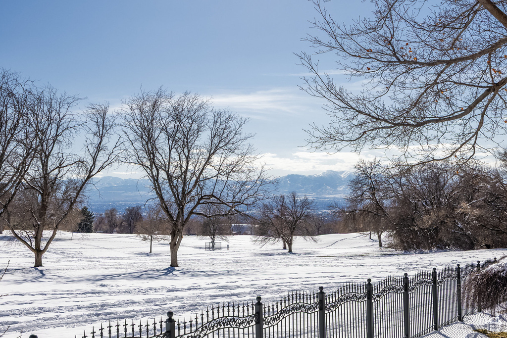 Snowy yard featuring a mountain view and fence