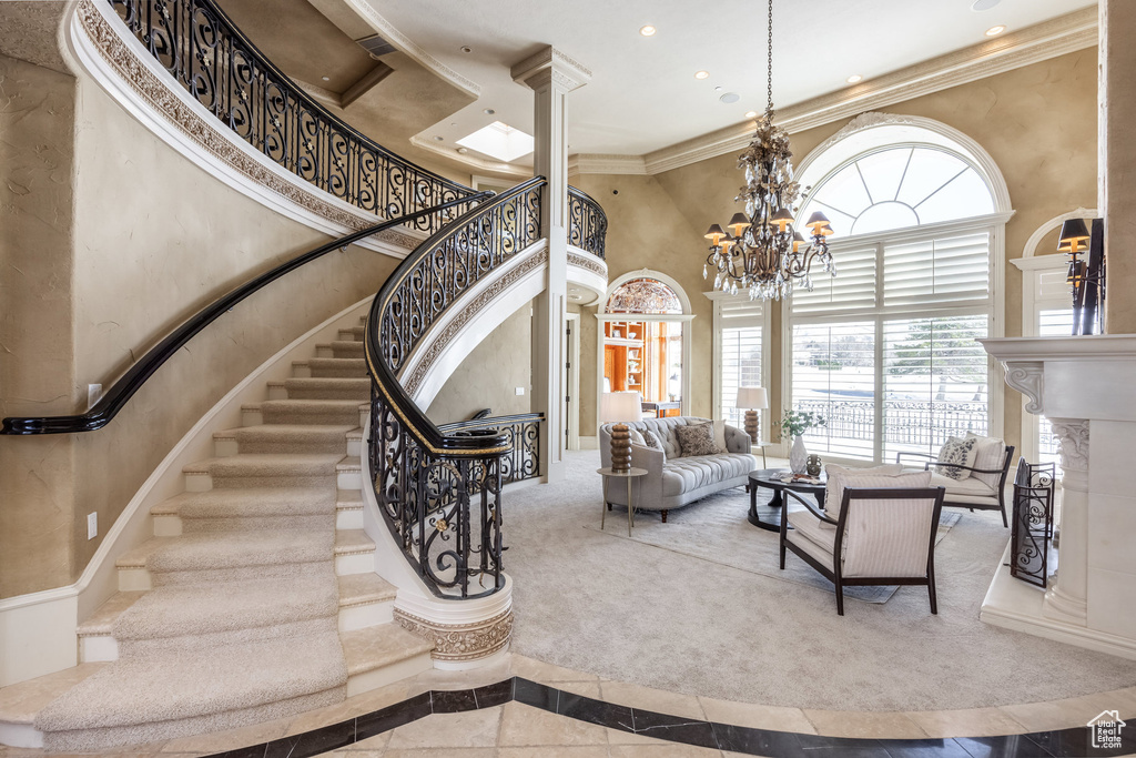 Stairway with ornamental molding, a high end fireplace, a towering ceiling, recessed lighting, and ornate columns