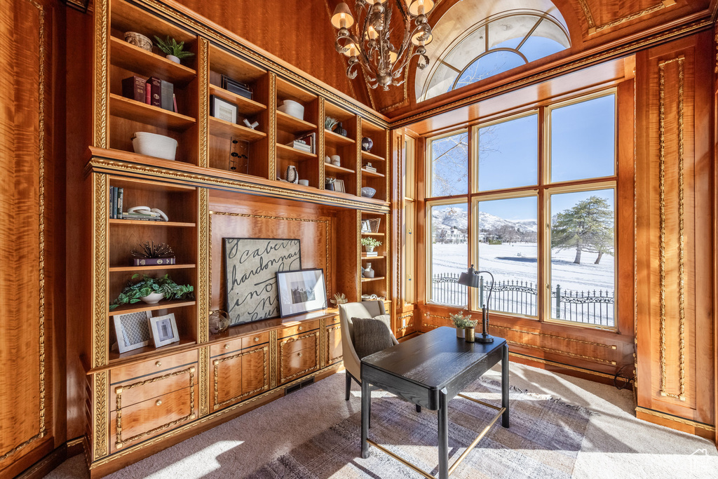 Office featuring vaulted ceiling, built in shelves, an inviting chandelier, and dark colored carpet