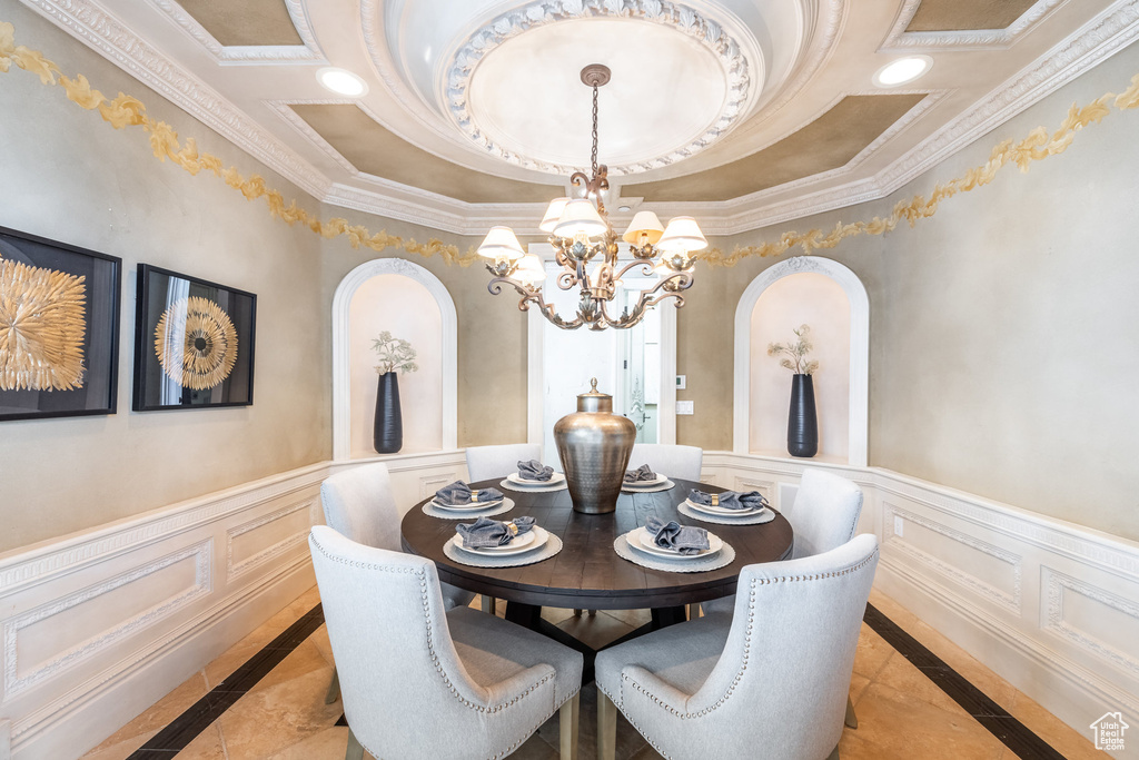 Dining space featuring ornamental molding, a notable chandelier, and wainscoting