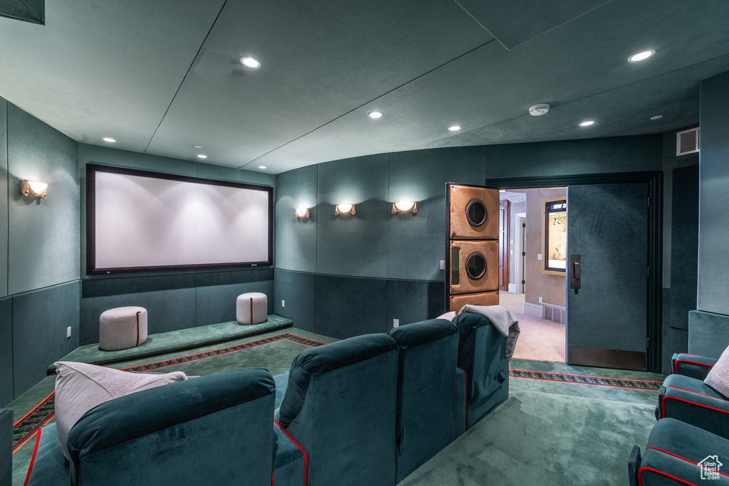 Carpeted cinema with stacked washer / dryer, visible vents, and recessed lighting