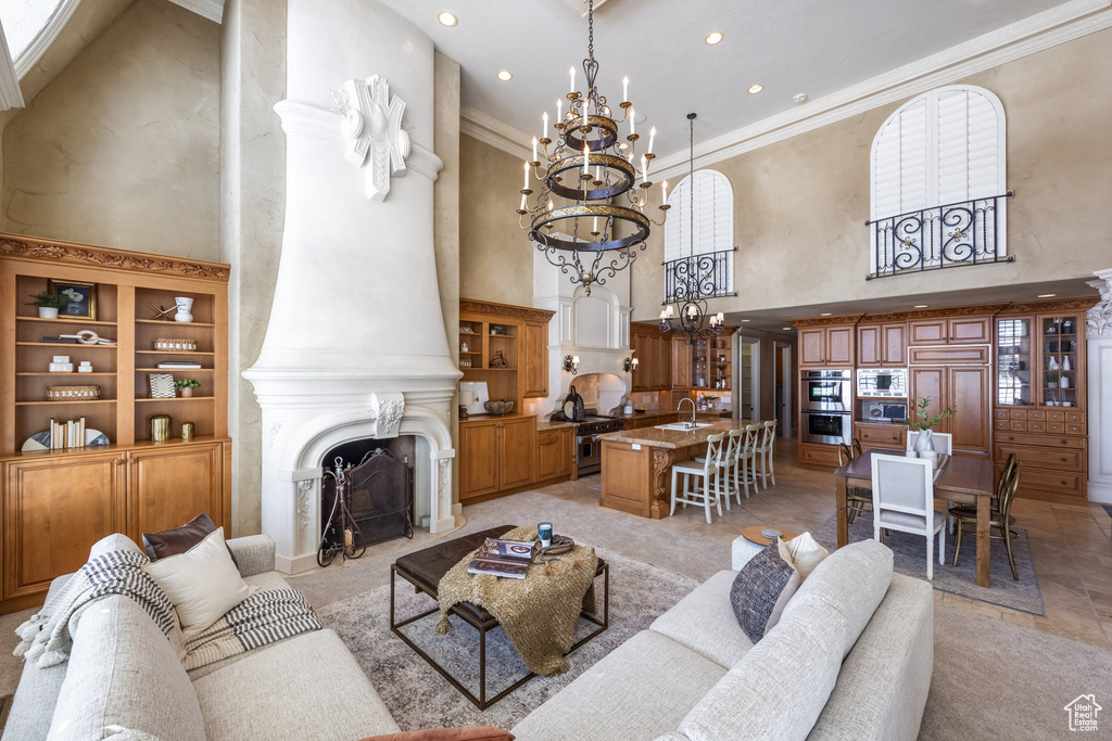 Living area with ornamental molding, a large fireplace, a towering ceiling, recessed lighting, and an inviting chandelier