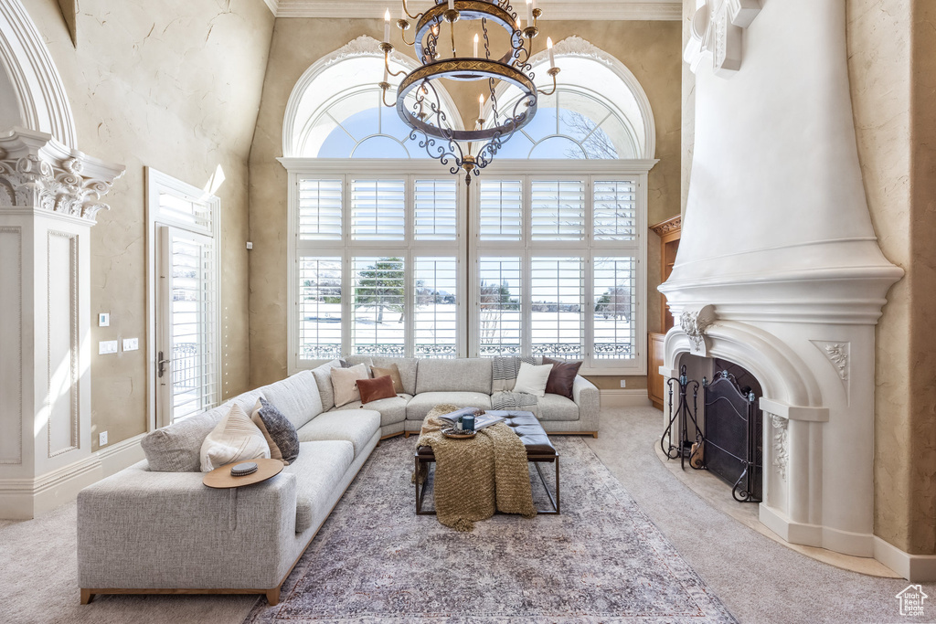 Living room featuring a chandelier, baseboards, a fireplace, a towering ceiling, and carpet floors
