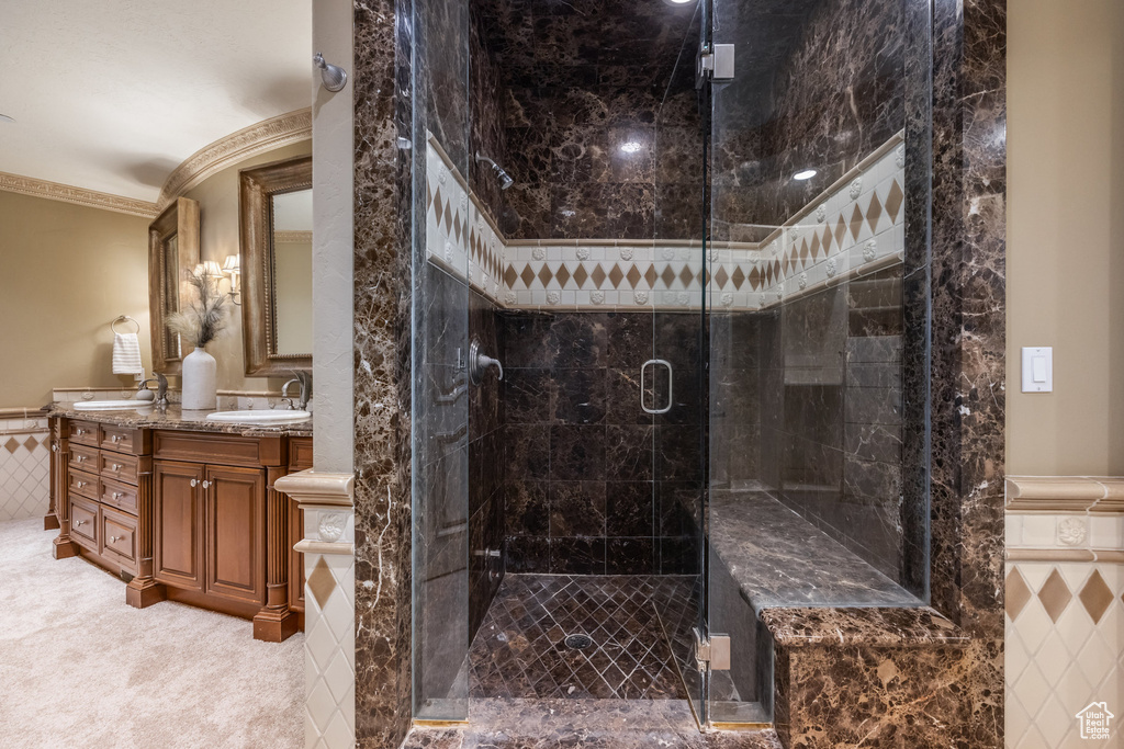 Full bath featuring ornamental molding, a shower stall, a wainscoted wall, a sink, and double vanity