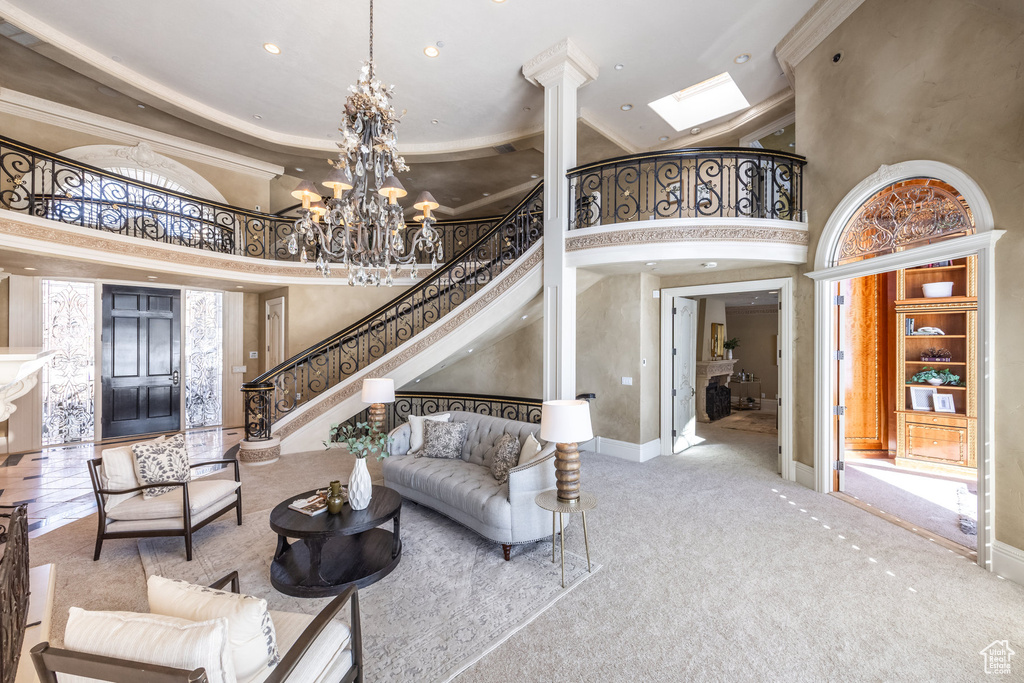 Carpeted living area with baseboards, a towering ceiling, stairway, and a notable chandelier