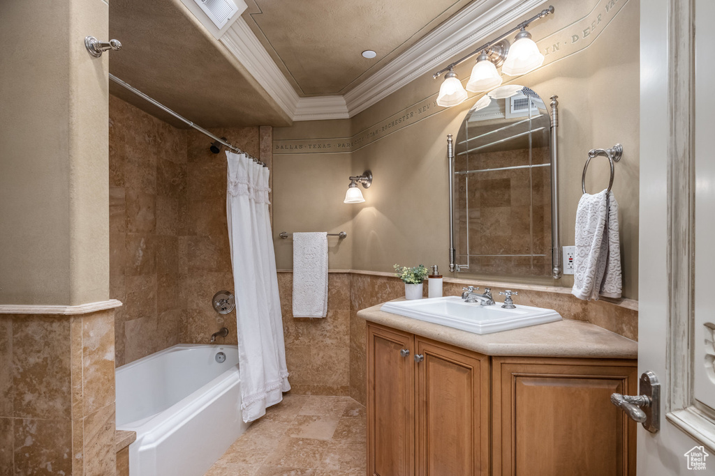 Full bathroom featuring tile walls, a wainscoted wall, visible vents, ornamental molding, and shower / bathtub combination with curtain