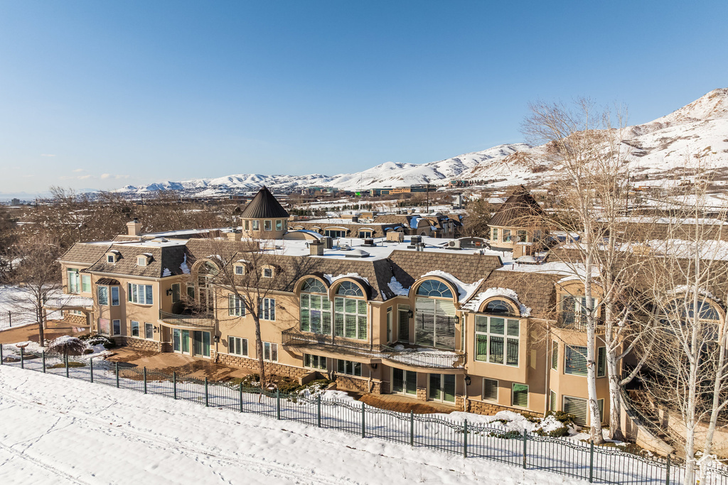 Snow covered building with a residential view, a mountain view, and fence private yard