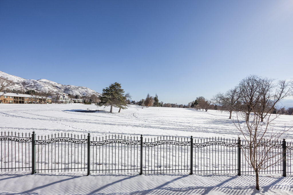 Yard layered in snow with fence and a mountain view