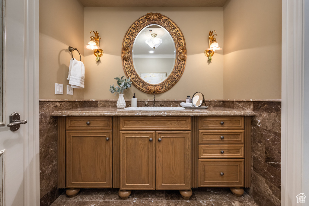 Bathroom featuring tile walls, wainscoting, and vanity