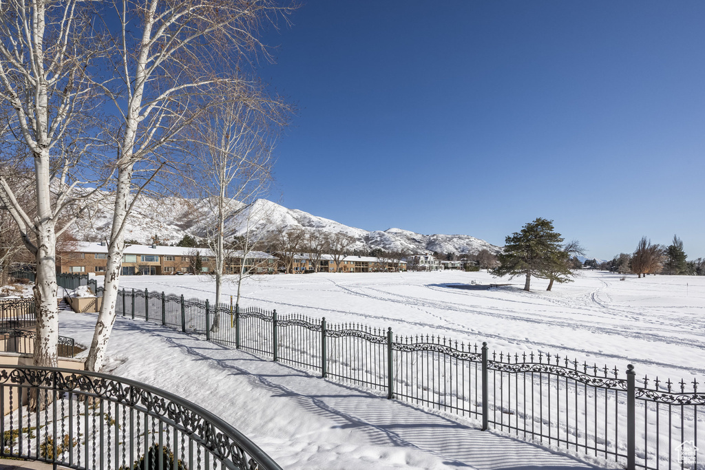 Snowy yard featuring fence and a mountain view
