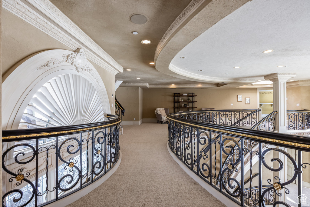 Hallway featuring decorative columns, an upstairs landing, crown molding, and carpet