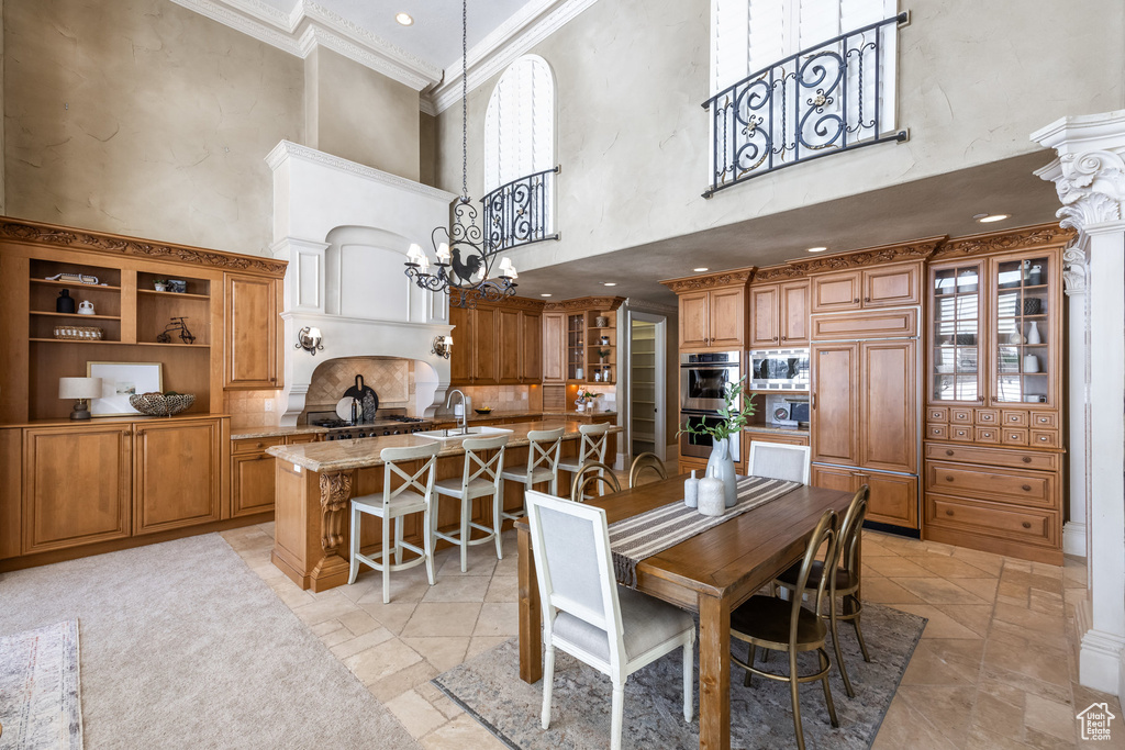 Dining space featuring a towering ceiling, a chandelier, and crown molding