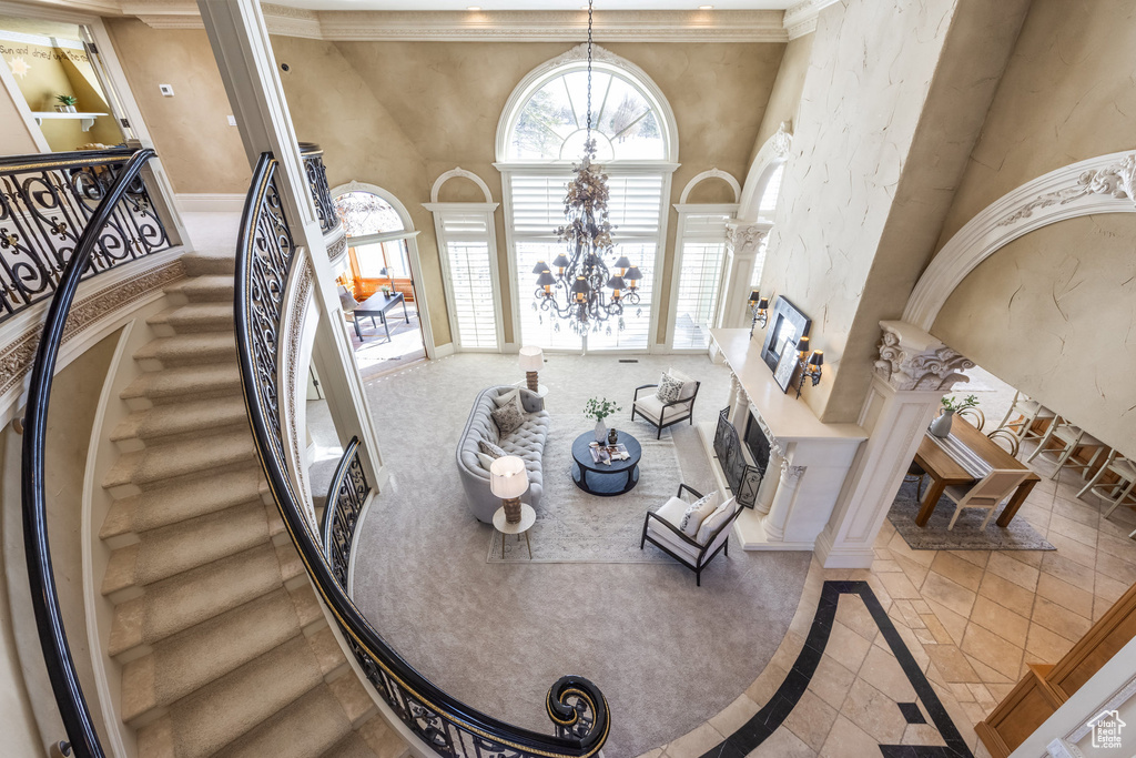 Interior space with decorative columns, crown molding, a notable chandelier, baseboards, and a towering ceiling