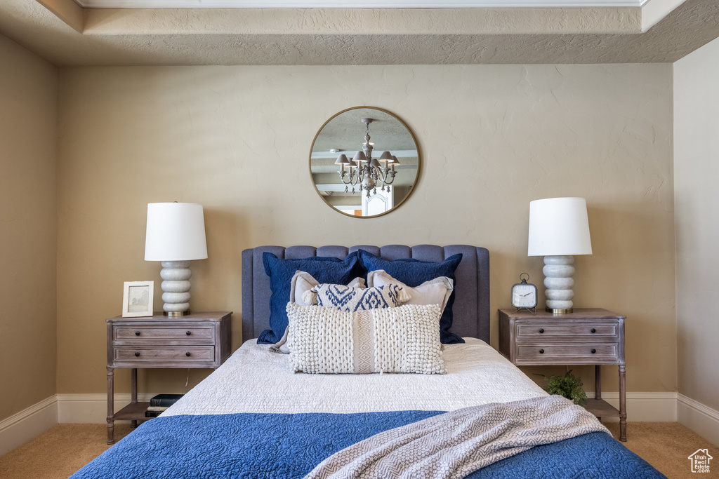 Carpeted bedroom with baseboards and a notable chandelier