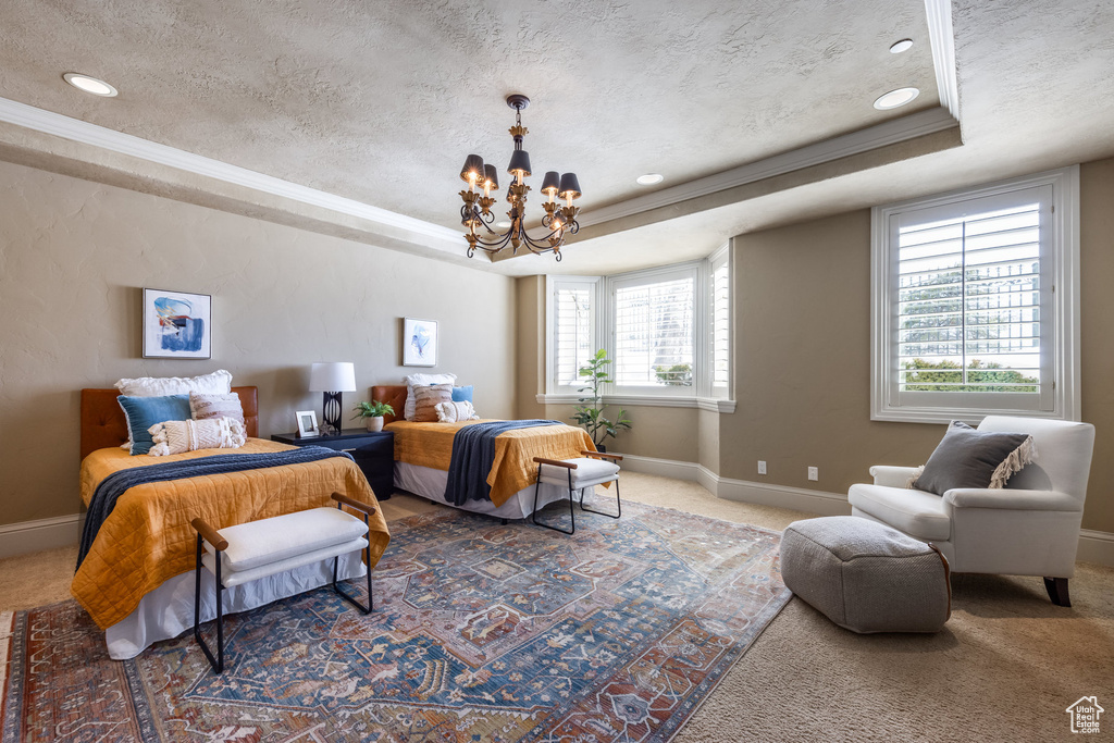 Bedroom featuring a raised ceiling, carpet floors, and a notable chandelier