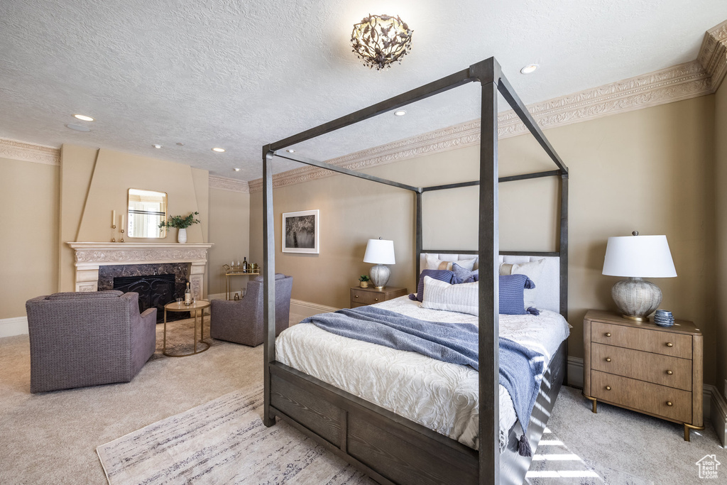 Bedroom featuring crown molding, carpet, baseboards, a textured ceiling, and a fireplace