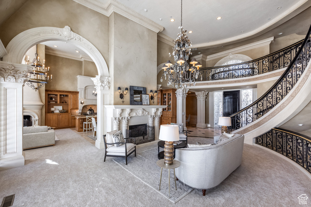 Carpeted living area featuring a chandelier, a towering ceiling, crown molding, and a fireplace