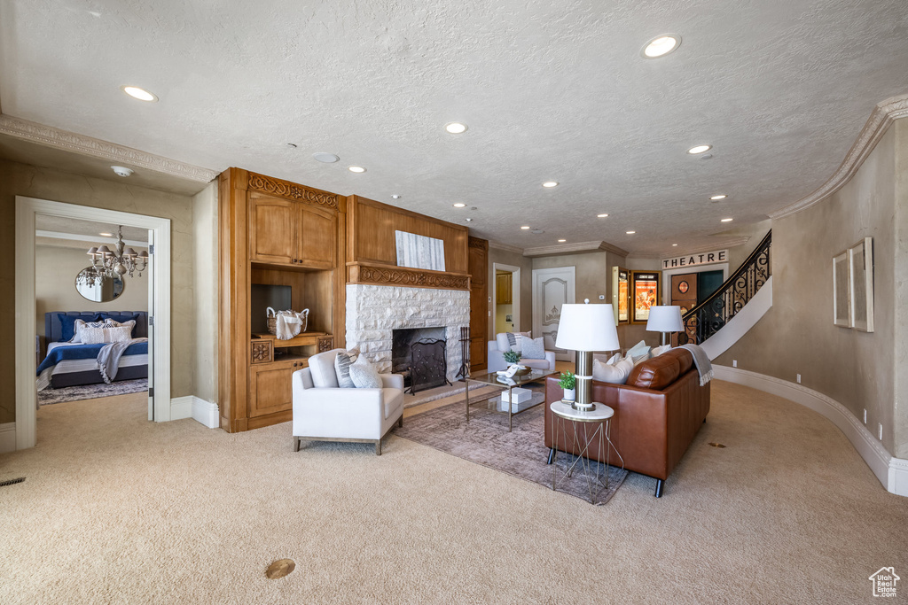 Living area featuring a textured ceiling, a fireplace, ornamental molding, and light colored carpet