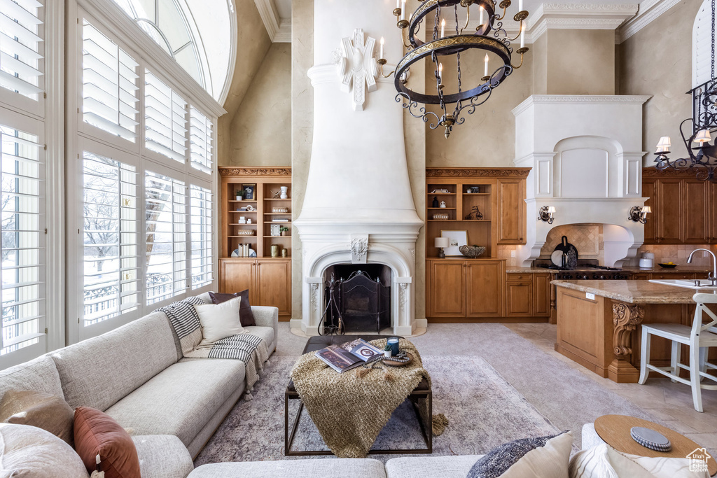 Living room with a fireplace, a high ceiling, a chandelier, and crown molding