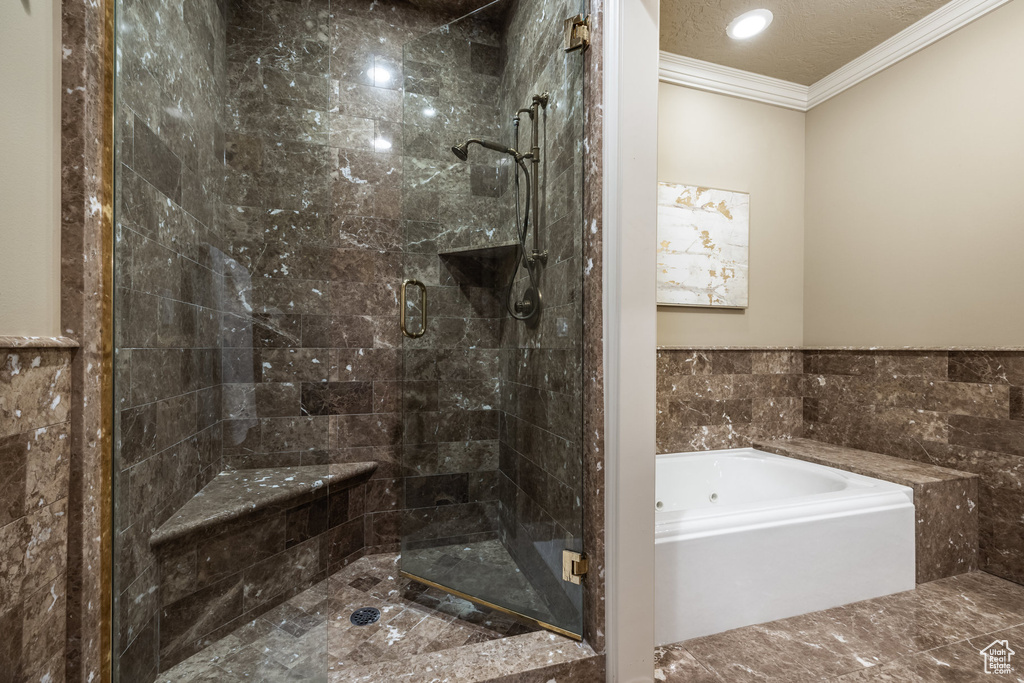 Bathroom featuring a shower stall, crown molding, a bath, and a textured ceiling