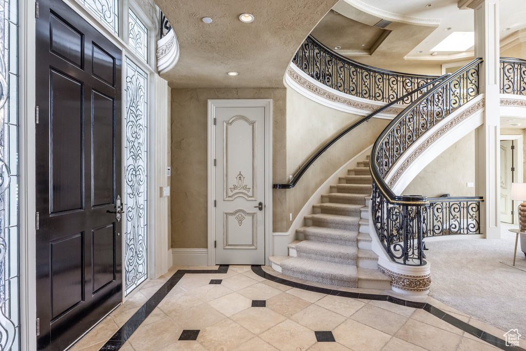 Entryway featuring a textured ceiling, baseboards, a towering ceiling, stairway, and recessed lighting