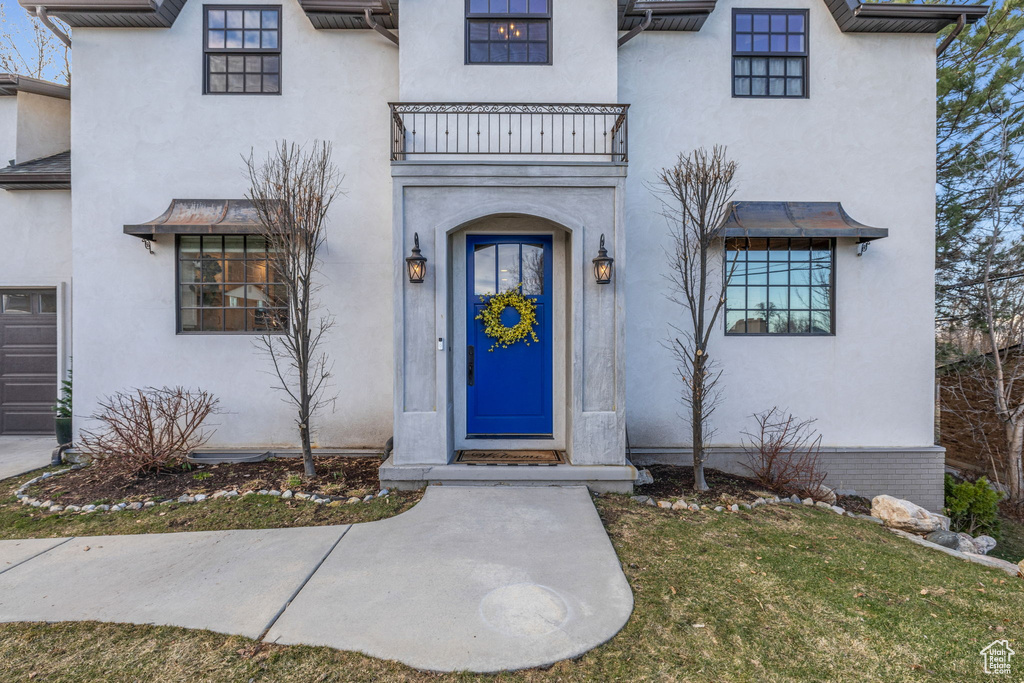 View of exterior entry with a balcony and stucco siding