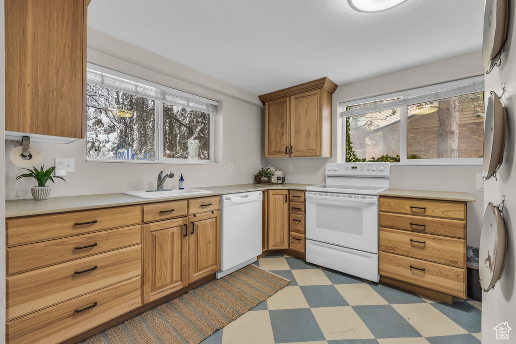 Kitchen featuring white appliances, light countertops, light floors, and a sink