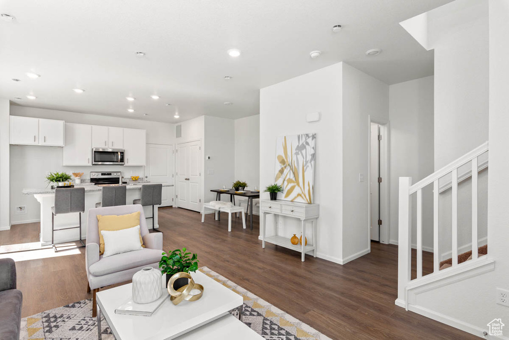 Living room with baseboards, dark wood-type flooring, stairway, and recessed lighting