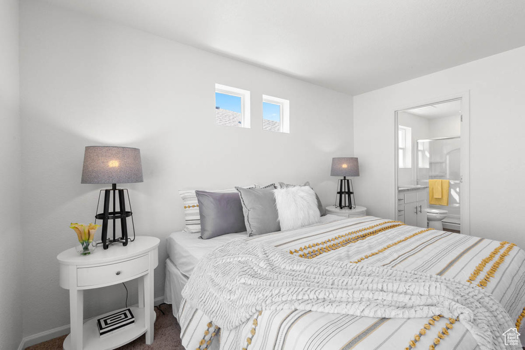 Bedroom with ensuite bathroom, baseboards, and carpet