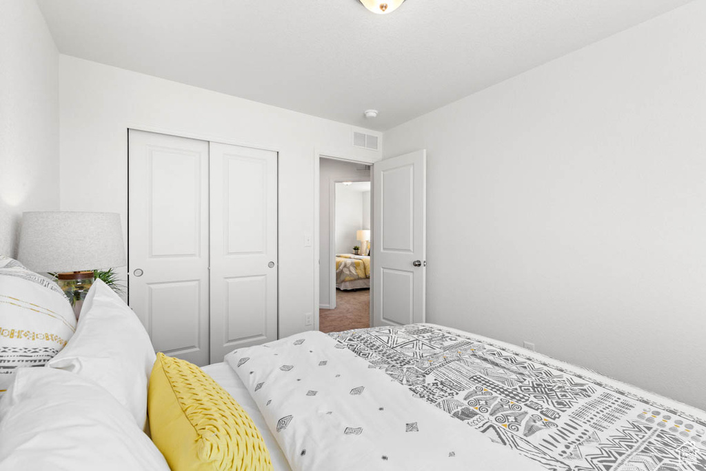 Carpeted bedroom with visible vents and a closet