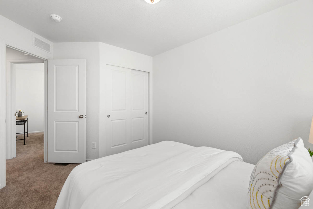Bedroom featuring visible vents, a closet, and dark carpet