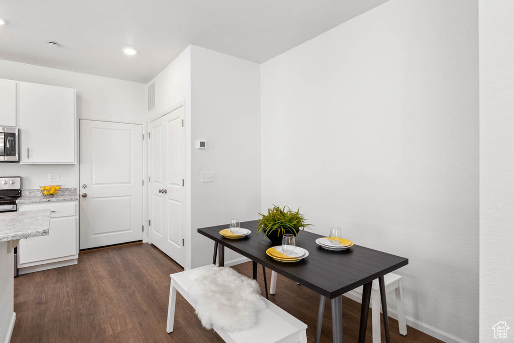 Dining area featuring dark wood finished floors, baseboards, visible vents, and recessed lighting