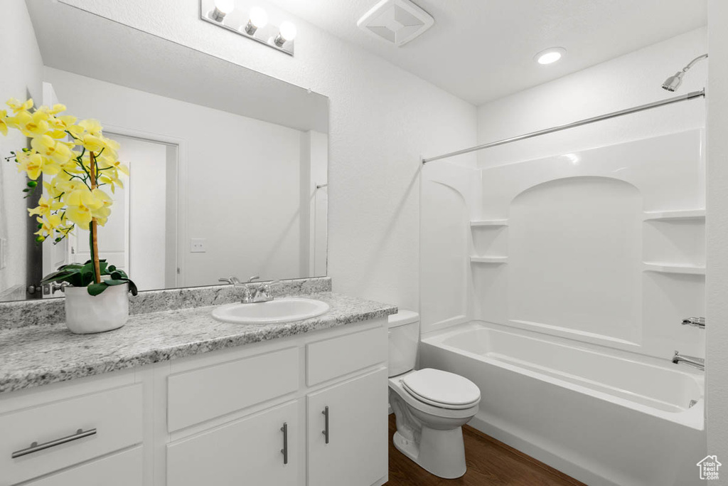 Bathroom featuring visible vents, toilet, wood finished floors, vanity, and shower / tub combination