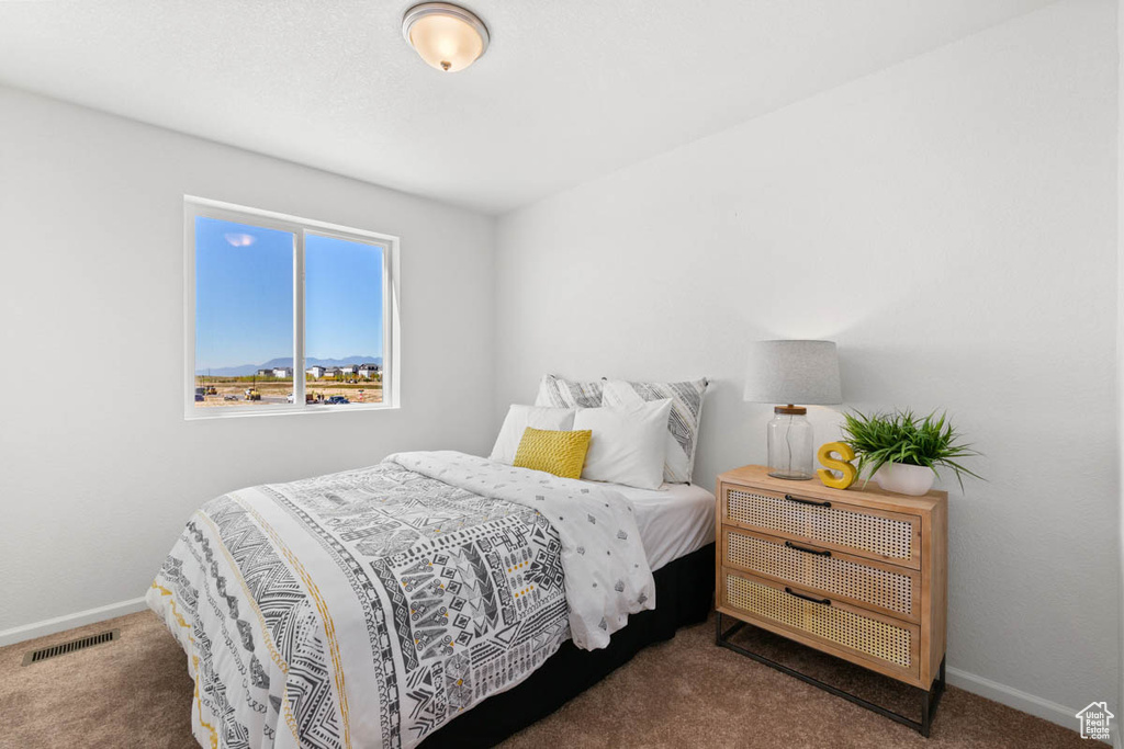 Carpeted bedroom with baseboards and visible vents