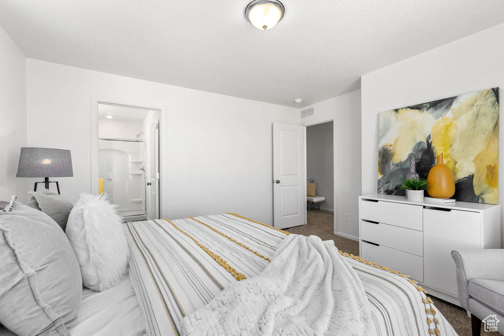 Carpeted bedroom with baseboards, ensuite bath, and visible vents