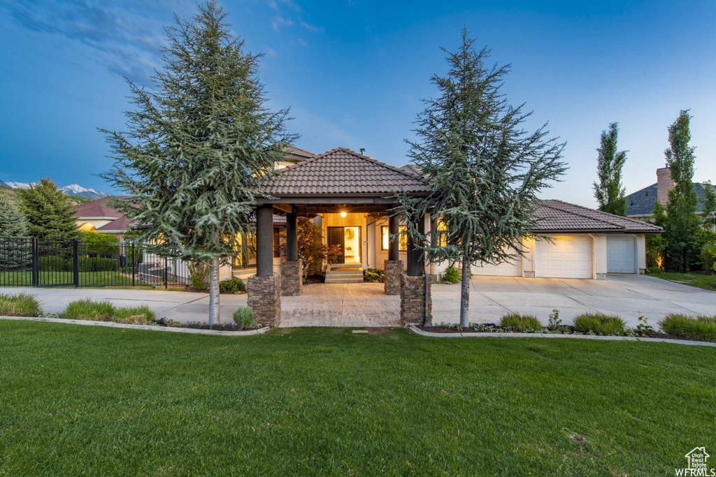 View of front of property with a tile roof, a front yard, fence, and concrete driveway