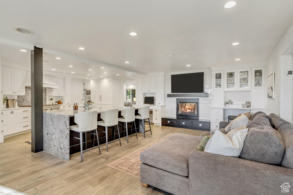 Living area with a fireplace, recessed lighting, and light wood-style floors