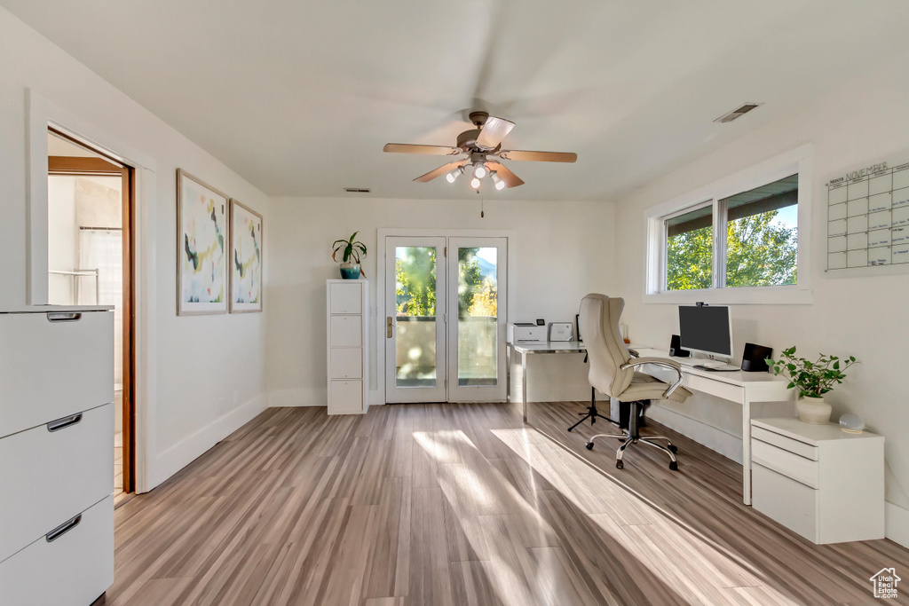 Office area with light wood-type flooring, visible vents, baseboards, and ceiling fan
