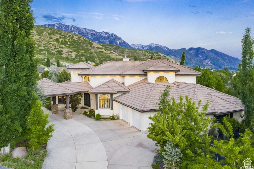 Mediterranean / spanish-style home featuring a tiled roof, stucco siding, a mountain view, and an attached garage