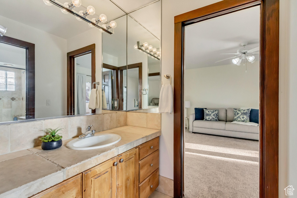 Bathroom with a ceiling fan, vanity, and decorative backsplash