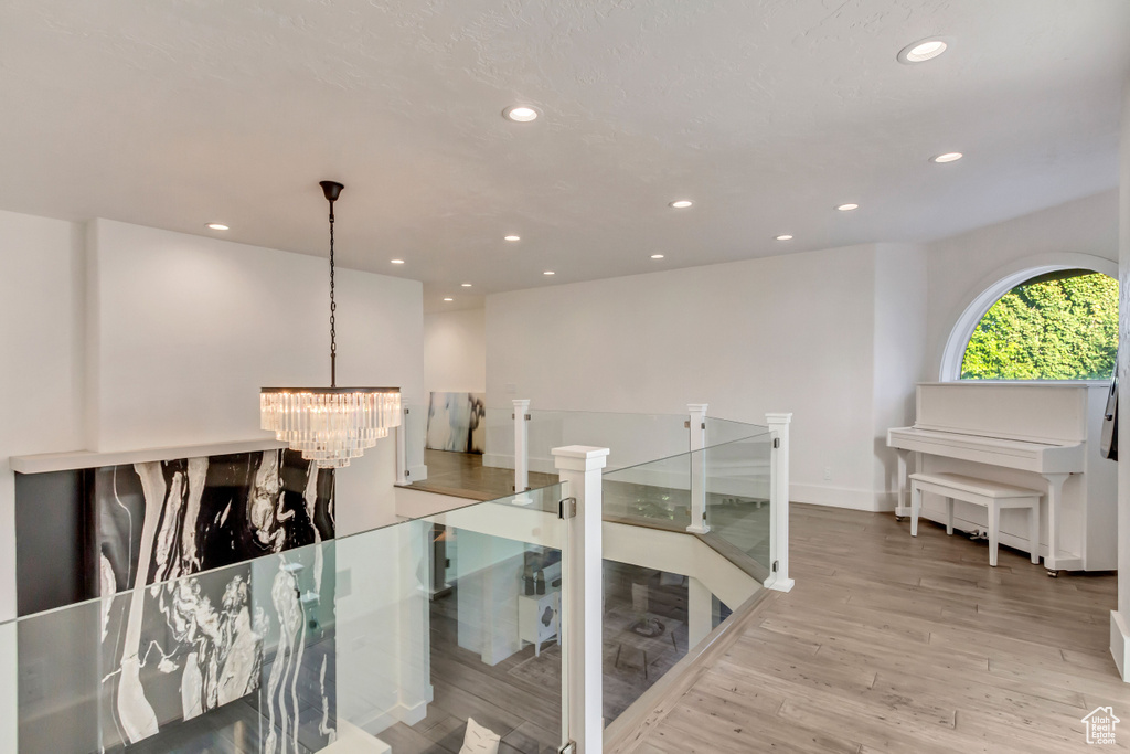 Hall with a notable chandelier, wood finished floors, an upstairs landing, and recessed lighting