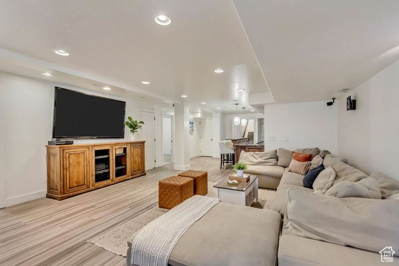 Living room with light wood-style floors, baseboards, and recessed lighting