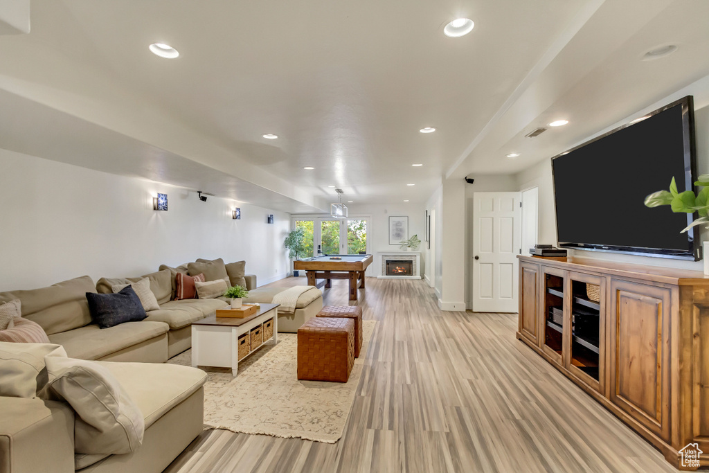 Living area featuring a warm lit fireplace, visible vents, recessed lighting, and light wood-style floors