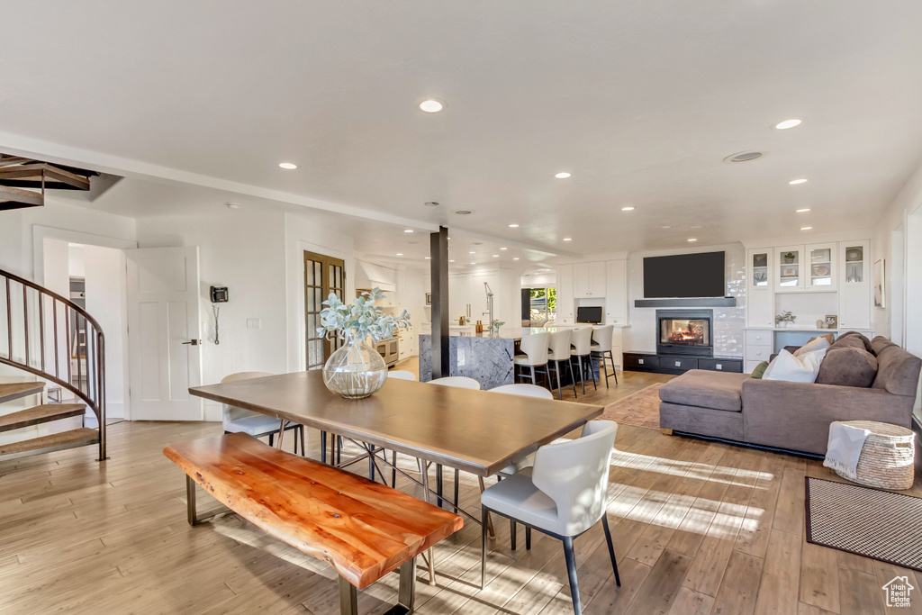 Dining room featuring light wood finished floors, recessed lighting, a multi sided fireplace, and stairway