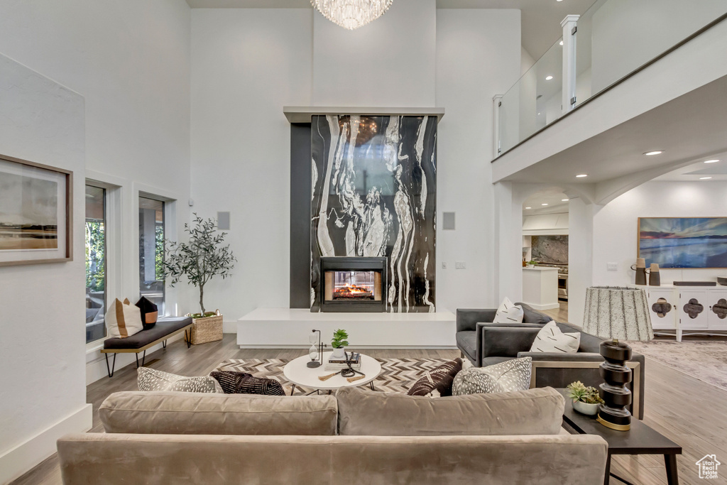 Living area featuring baseboards, a high ceiling, wood finished floors, and a multi sided fireplace