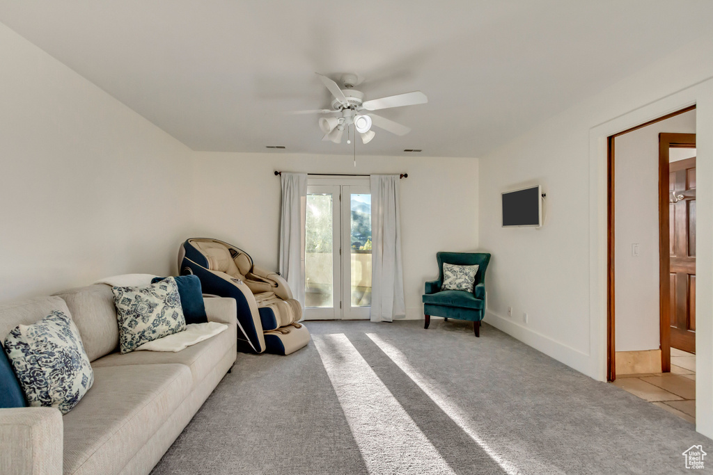 Living room with light carpet, visible vents, and ceiling fan