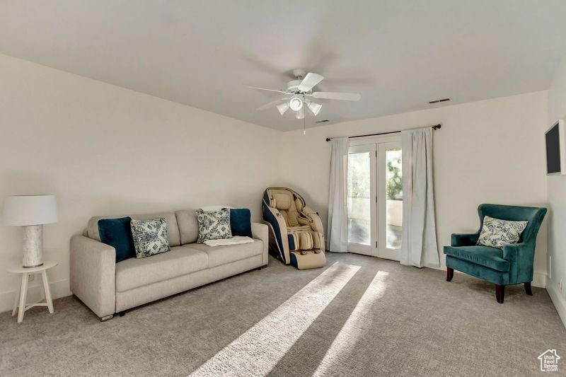 Carpeted living room featuring visible vents and a ceiling fan