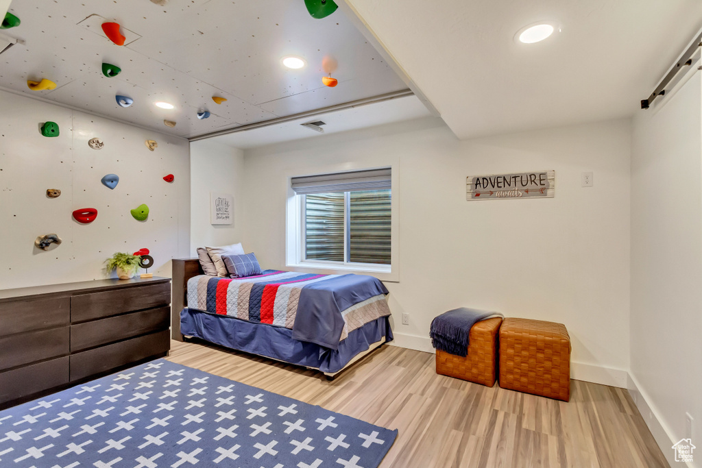Bedroom featuring baseboards, a barn door, wood finished floors, and recessed lighting