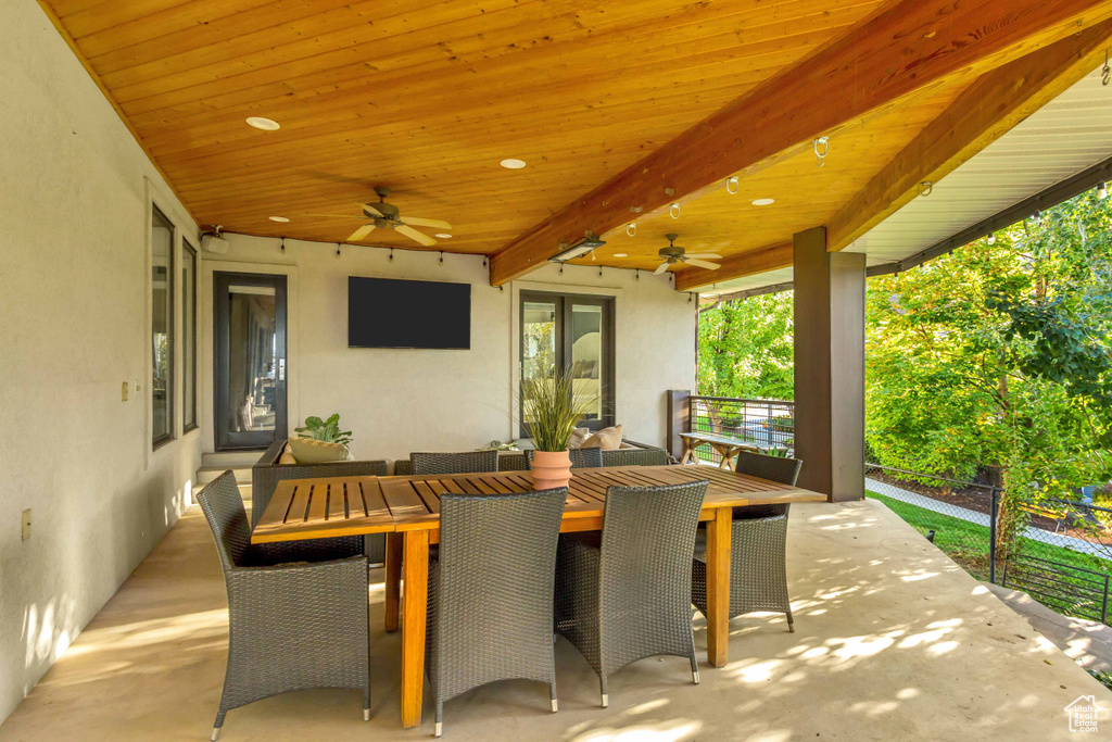 View of patio with fence, outdoor dining space, and a ceiling fan